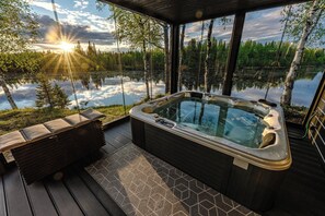 A hot tub on a deck with a view of a lake and trees. - The Iconic Wikkelä Villa (Ranua)