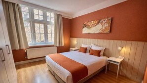A bedroom with a large bed, a window with curtains, a painting on the wall, and a wooden floor. - St-Jan (De Drie Koningen) - 175m² - 250m from Market Square (Brugge)