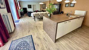 A modern kitchen with a central island, pendant lighting, and a dining area with a table and chairs. - St-Jan (De Drie Koningen) - 175m² - 250m from Market Square (Brugge)