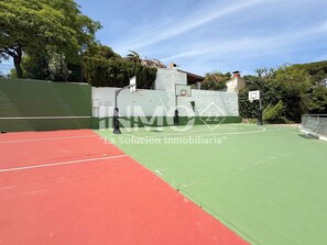 An outdoor basketball court with a red and green playing surface, surrounded by a green fence and trees. - 1st line beach flat - Edif. Olimpic  (Cambrils)