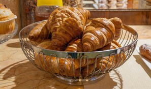 A metal basket filled with croissants on a marble countertop. - Mihlton Barcelona Boutique B&B (Barcelona)