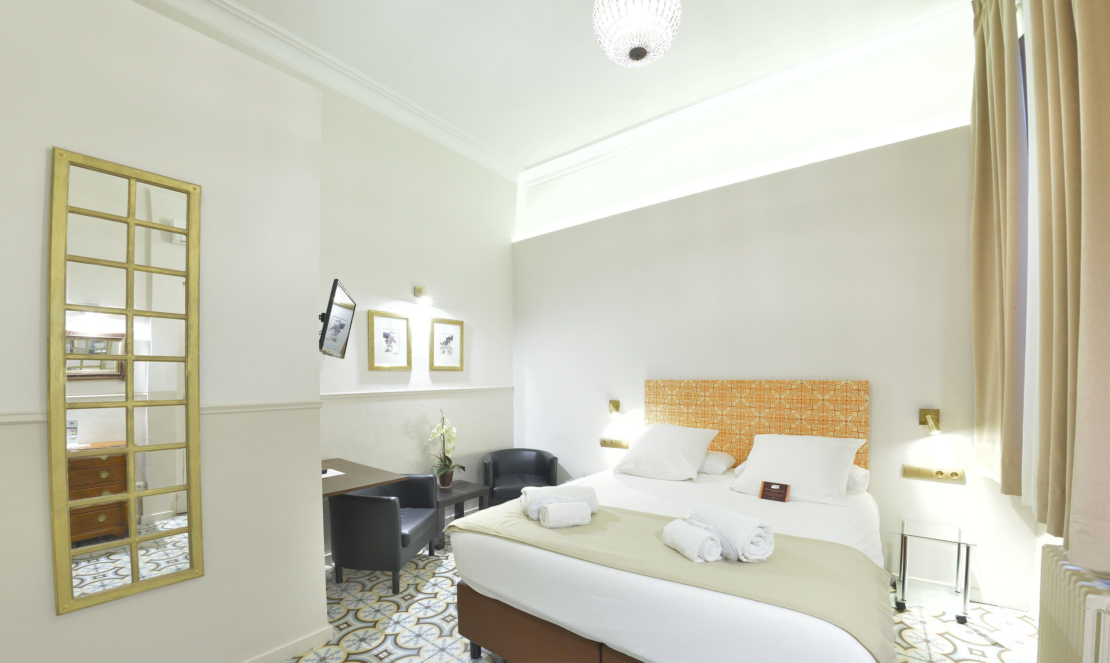 Una habitación de hotel con cama, escritorio, silla y espejo.