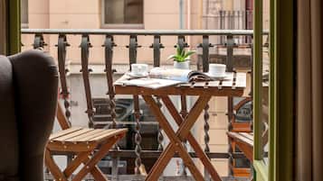 Un balcón con una mesa de madera, una silla y una planta en maceta.
