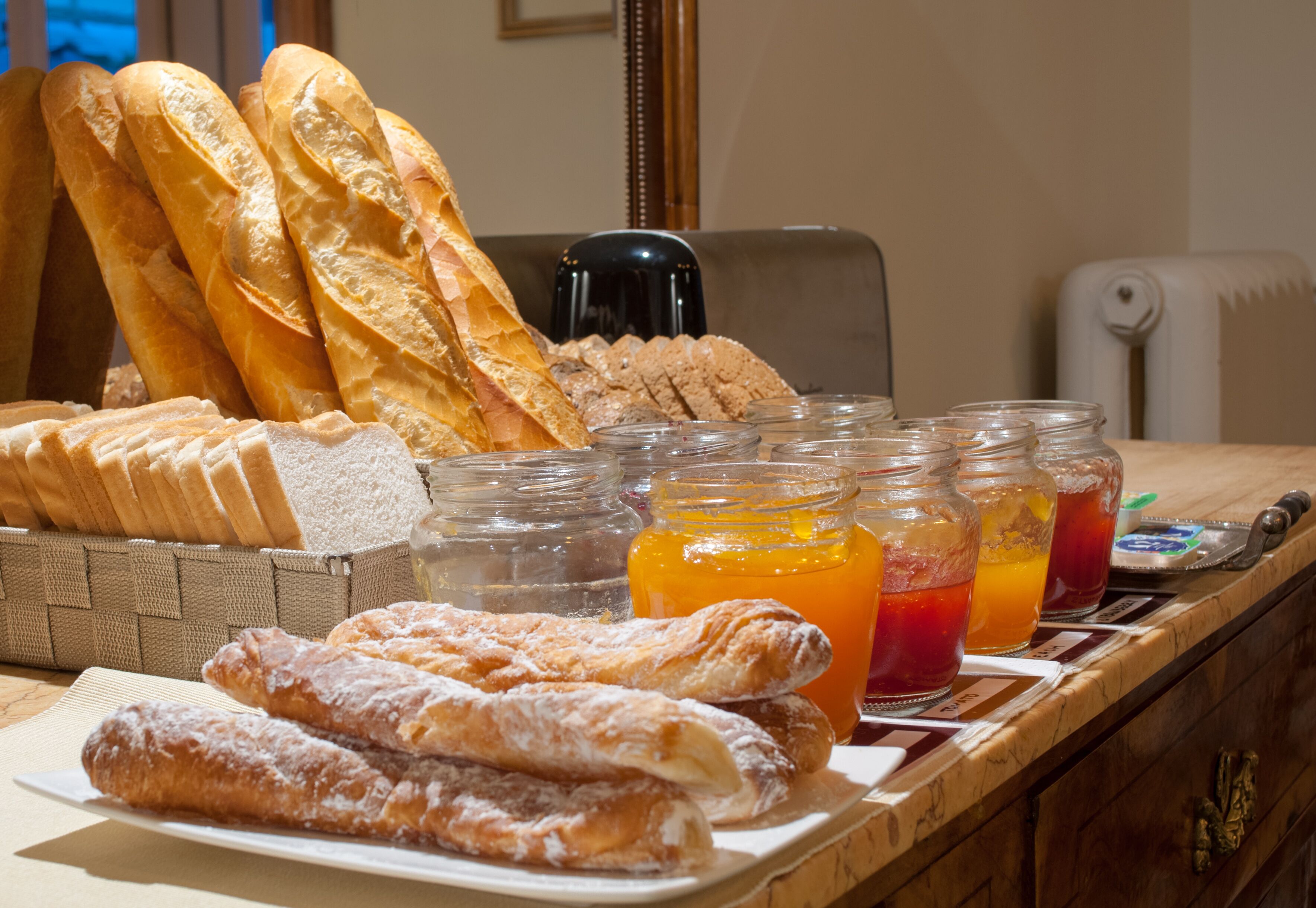 Une table de petit-déjeuner avec du pain, des viennoiseries et des confitures de fruits.