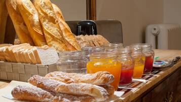 Une table de petit-déjeuner avec du pain, des viennoiseries et des confitures de fruits.