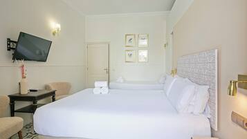 Habitación de hotel con una cama grande, un televisor de pantalla plana en la pared, una mesita de noche con lámpara y una puerta con espejo.
