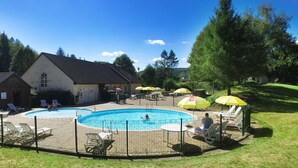 Ein Schwimmbeckenbereich mit Liegestühlen und Sonnenschirmen.