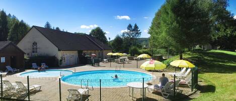 A swimming pool area with lounge chairs and umbrellas.