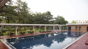 Ein Pool mit überdachter Sitzgelegenheit und Liegestühlen.