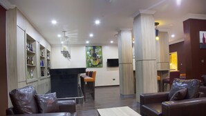 Eine moderne Lobby mit Ledersofas, einem Holztisch und einer Bar mit Regalen.