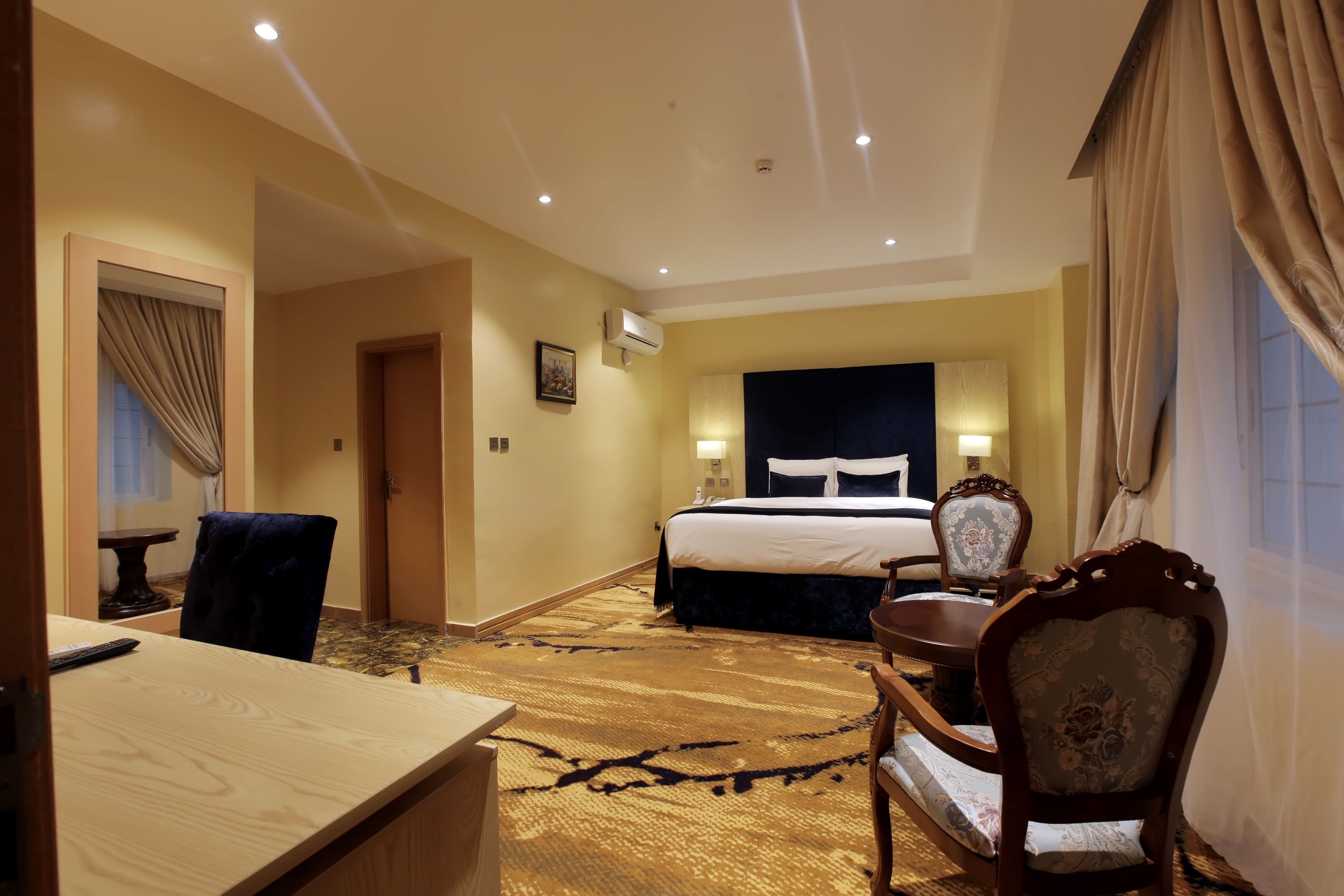 Une chambre d’hôtel avec un grand lit, un bureau, une chaise et un sol recouvert de moquette.