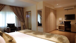 Ein Hotelzimmer mit Bett, Schreibtisch, Stuhl, Kleiderschrank und Fernseher.
