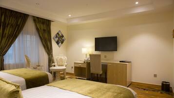 A hotel room with two beds, a desk, a chair, a television, and a painting on the wall.