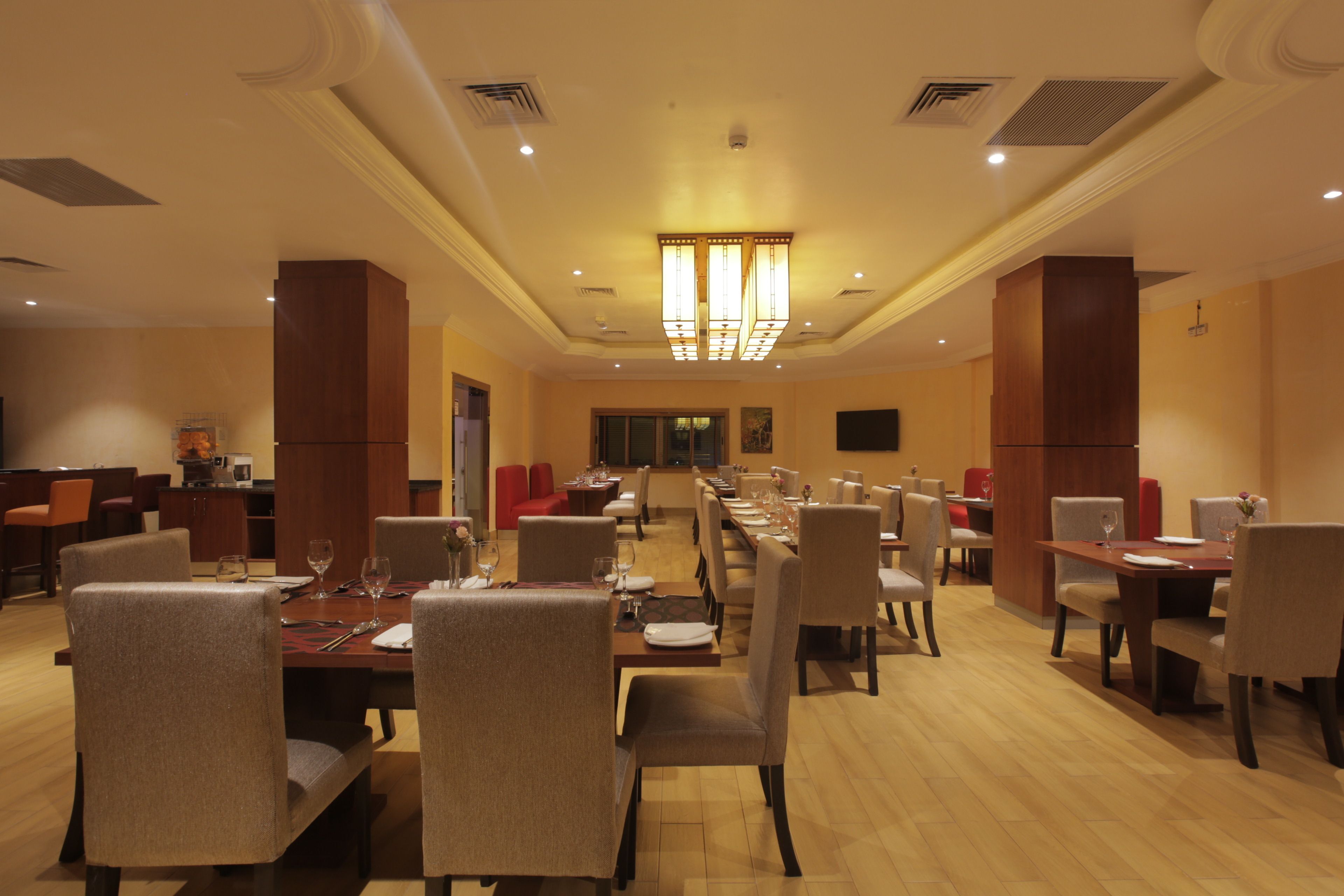 A spacious dining area with multiple tables and chairs, a long counter, and a chandelier.