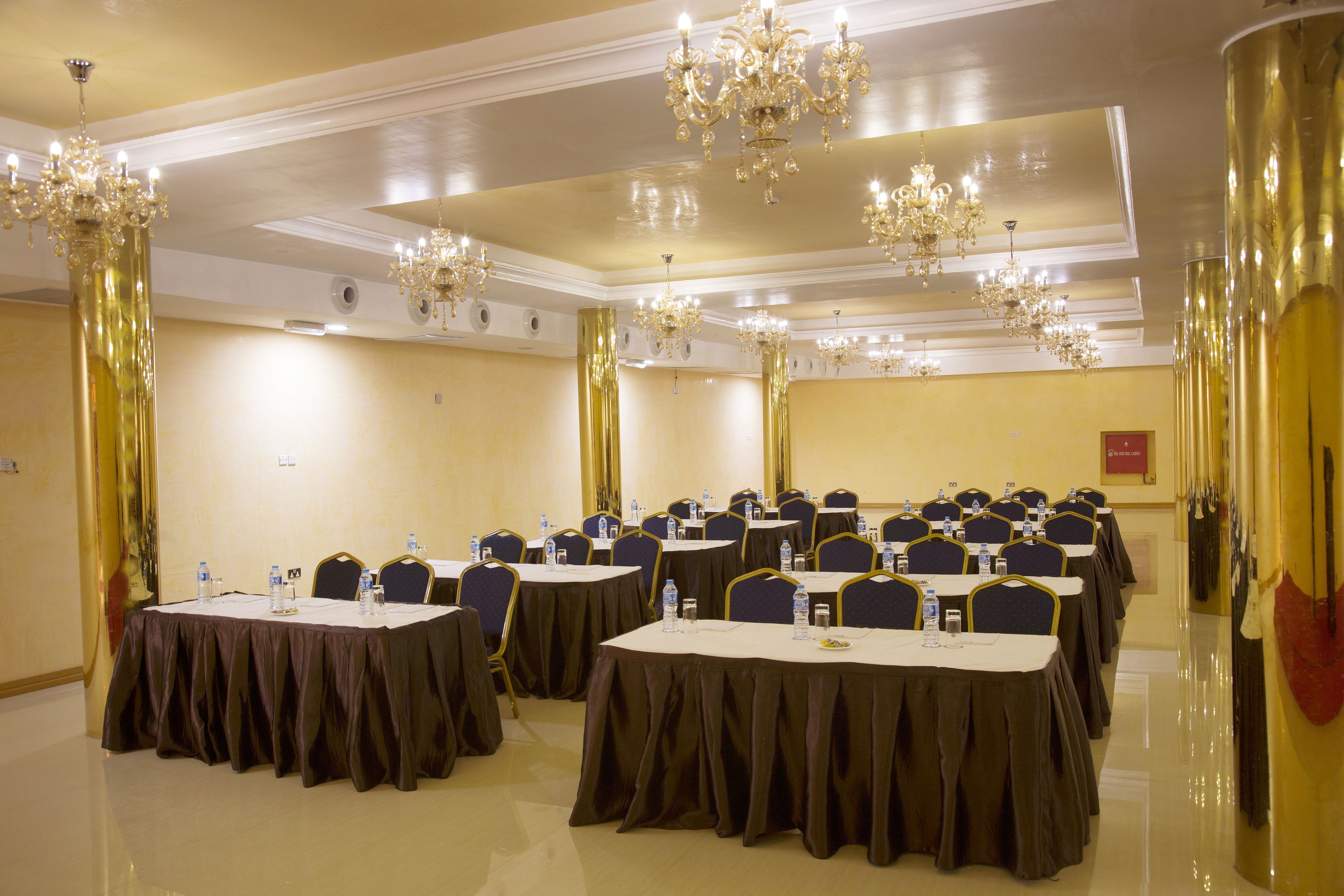 Uma sala de conferências com mesas redondas, cadeiras e lustres.