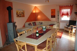 Un coin repas avec une table dressée pour deux personnes, un canapé et un téléviseur en arrière-plan.