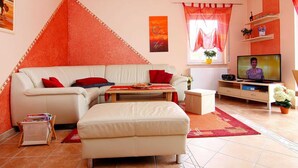 A living room with a sofa, ottoman, and a television. - Vacation cottage Albatros, Germany (Karlshagen)