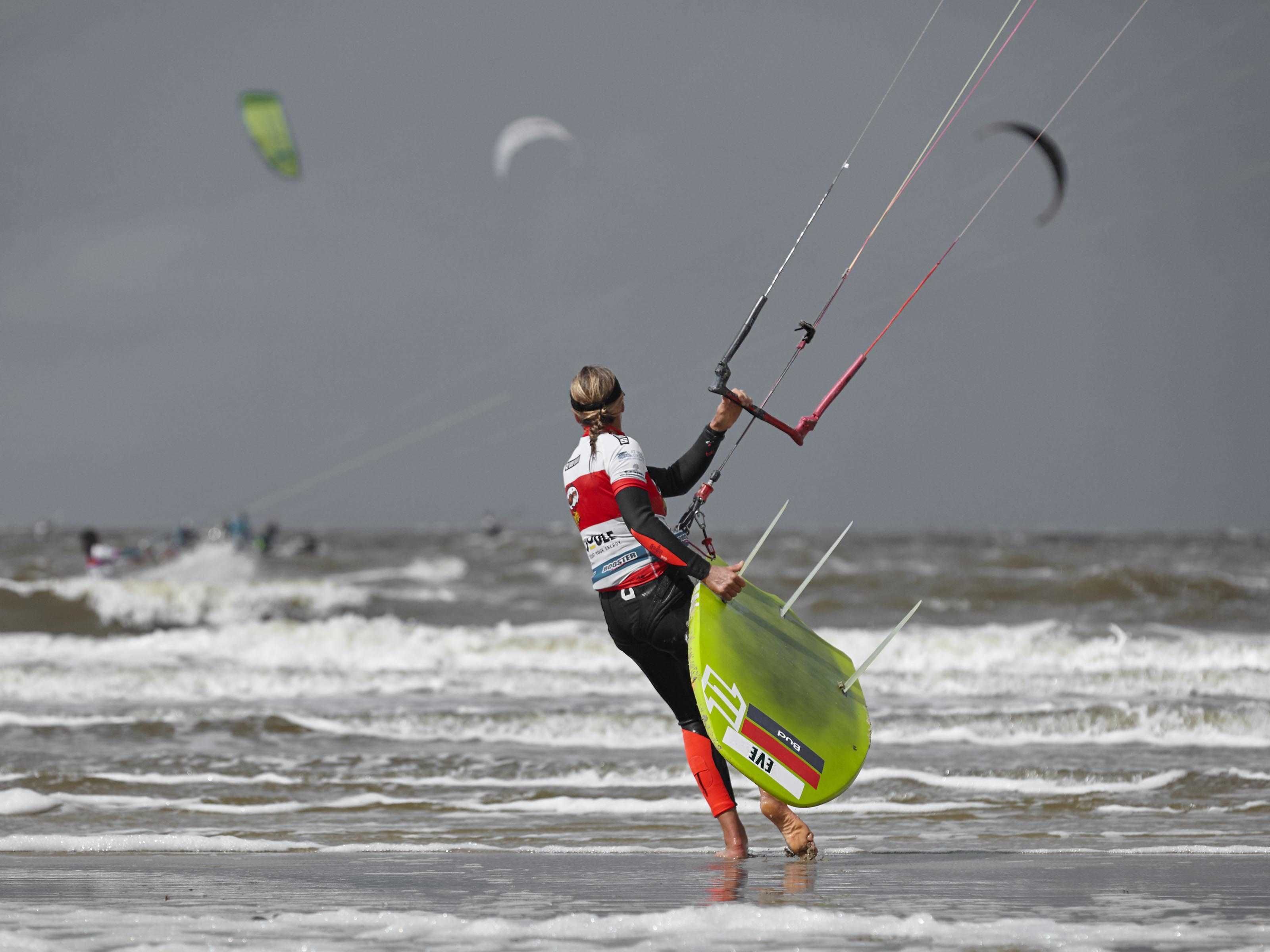 A person with a kiteboard walking on the beach.