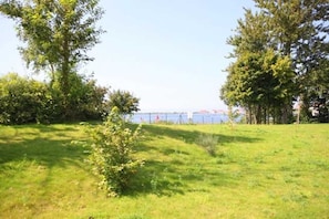 A grassy area with trees and a view of a body of water.