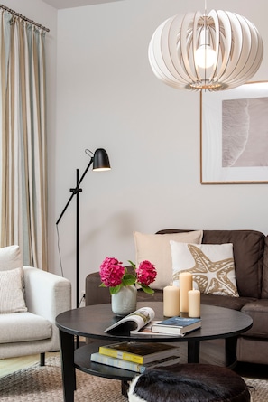 A modern living room with a round coffee table, a sofa, a floor lamp, and a hanging light fixture. - Alte Wäscherei 3, Germany (List)
