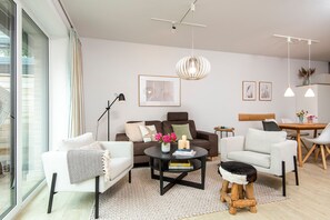 A modern living room with a sofa, armchairs, a coffee table, and a dining area.