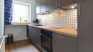 Una cucina moderna con mobili grigi, un piano di lavoro in legno e una parete di fondo rivestita di piastrelle.
