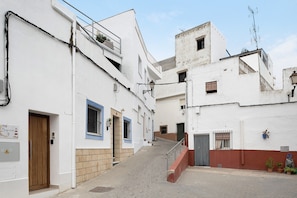 Una calle estrecha con edificios, una puerta de madera y una escalera.