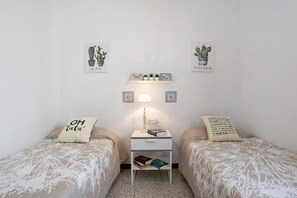 Un dormitorio con dos camas, una mesita de noche, una lámpara y decoración en la pared.