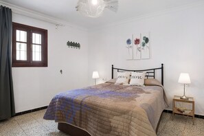 A bedroom with a bed, two bedside tables with lamps, a window with curtains, and wall art. - Holiday Home "Casa Boqueron" with Sea View, Rooftop Terraces and Wi-Fi (Conil de la Frontera)