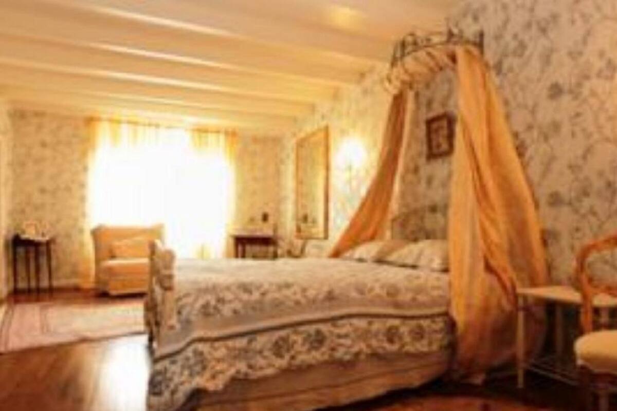 A bedroom with a four-poster bed, a nightstand, and a chair.