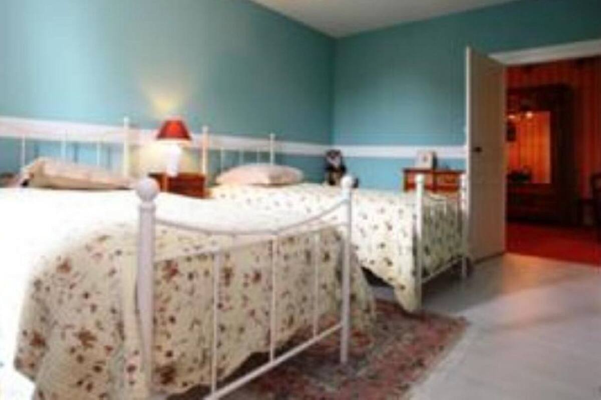 A bedroom with two beds, a red lamp, and a door leading to another room.