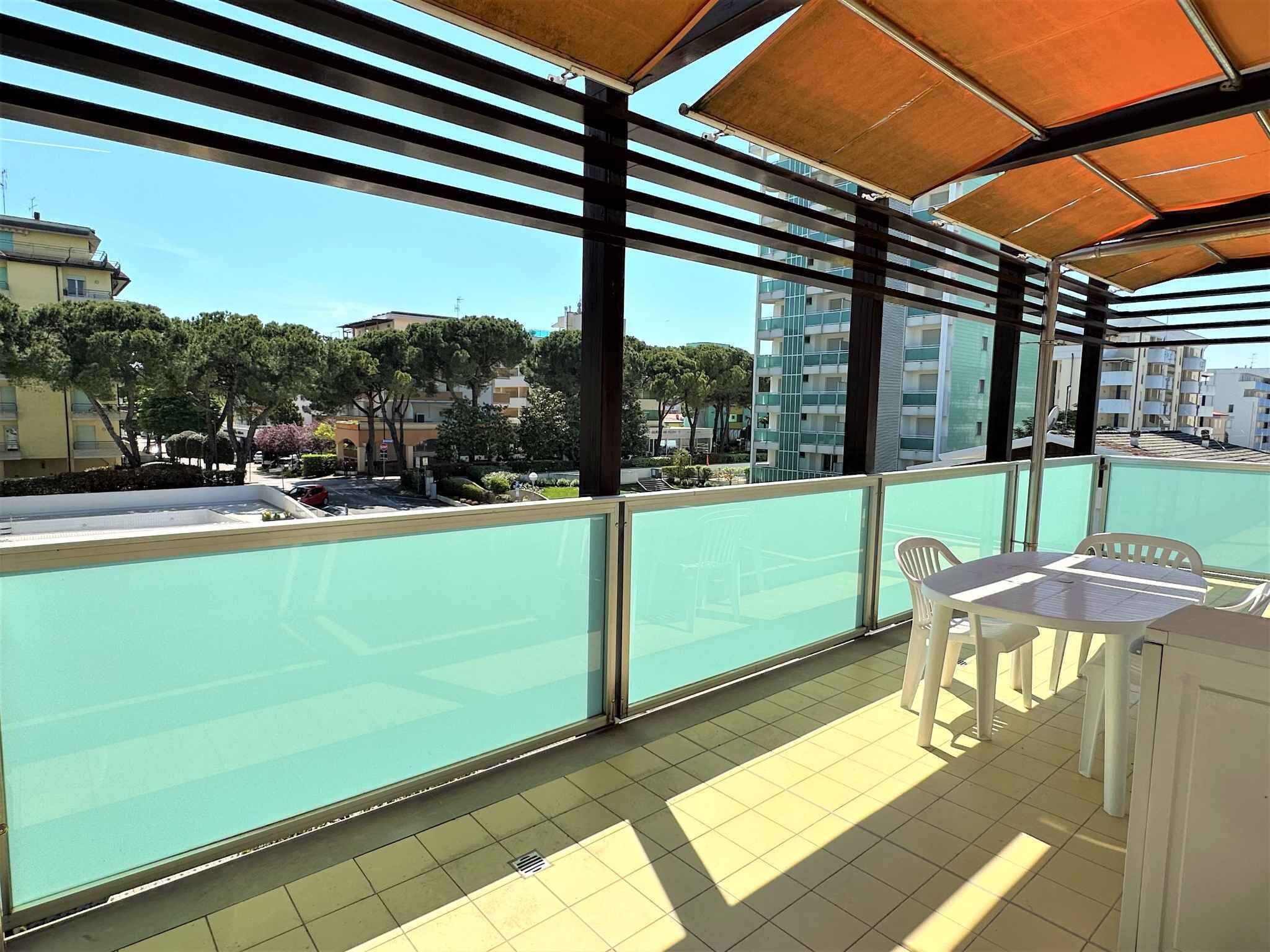 A balcony with a view of a residential area, featuring a table and chairs, and a tiled floor.