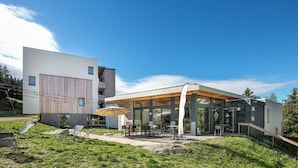 A modern building with a covered patio area, outdoor seating, and a grassy lawn. - VVF Les 7 Laux Massif de Belledonne, Prapoutel (Les Adrets)
