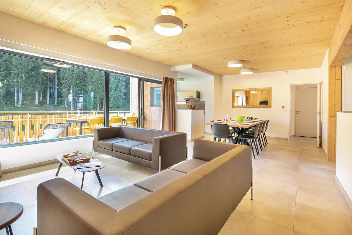 Ein modernes Wohnzimmer mit einer Couch, einem Couchtisch und einem Essbereich mit Stühlen und einem Tisch.