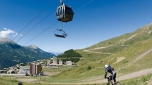 Ein Mountainbike-Weg mit einer Seilbahn im Hintergrund.