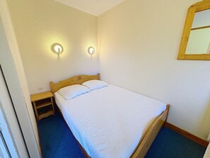 A single bed with a wooden headboard, two wall-mounted lights, and a small wooden nightstand.