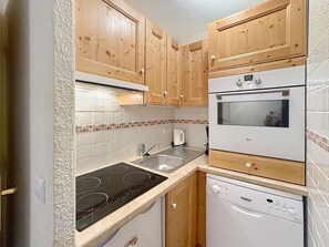A compact kitchen with wooden cabinets, a built-in oven, a dishwasher, and a stove.