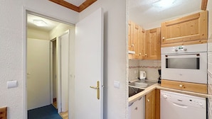 A compact kitchen with wooden cabinets, a built-in oven, and a dishwasher.