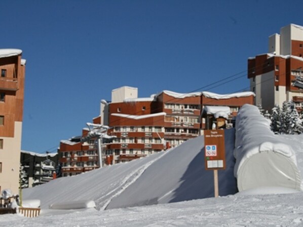 Une piste de ski enneigée, avec des bâtiments visibles au loin.