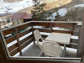 Enjoy the serene snowy landscape from this balcony with a table and two chairs.