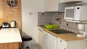 Une cuisine équipée d’un plan de travail en bois, d’un évier, d’un four à micro-ondes et d’une bouilloire.