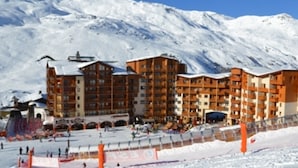 A multi-story hotel with a ski slope in the foreground.