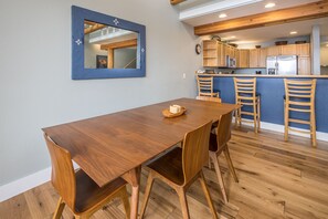 Un coin repas avec une table et des chaises en bois, un miroir à cadre bleu et des meubles en bois en arrière-plan.