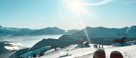 A ski slope with a clear view of the mountains and a ski lift in the background.
