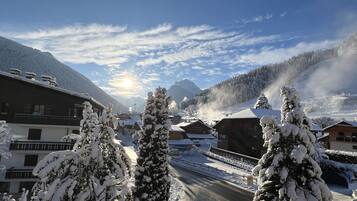 A snowy mountain village with wooden buildings, a clear sky, and a sunlit landscape.