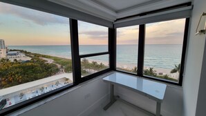 A room with a large window overlooking a beach and ocean.