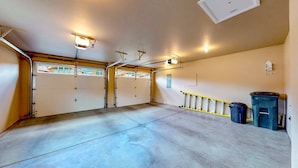 Eine Garage mit zwei weißen Türen, einem Betonboden und einer gelben Schutzvorrichtung.