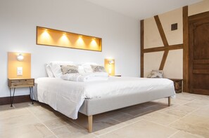 A modern bedroom with a large bed, two bedside tables, and wall-mounted lighting. - Jardin des Sens (Éguilly)