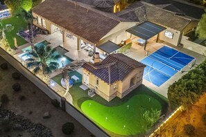 Imóvel residencial com piscina, quadra de tênis e um terraço coberto.