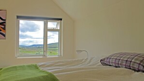 A bedroom with a bed, a window with a view of a landscape, and a lamp. - Öndólfsstaðir Farm B&B (Laugar)
